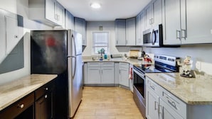Une cuisine moderne avec des meubles gris, un réfrigérateur en acier inoxydable, un four à micro-ondes et une cuisinière.