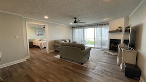 A spacious living room with hardwood flooring, a grey sofa, a flat-screen TV, and a fireplace.