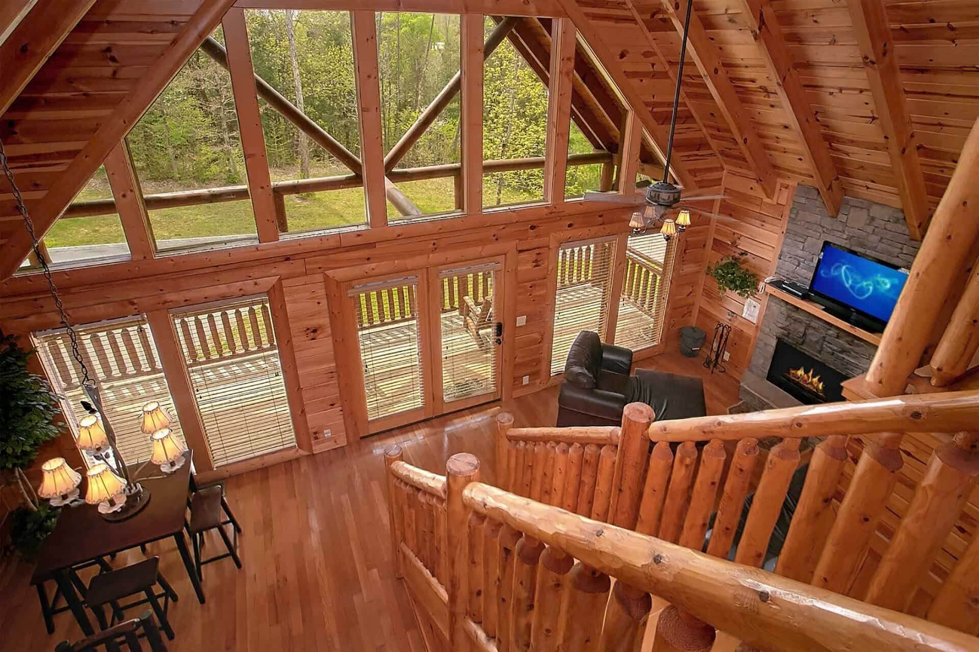 A wooden cabin interior with a dining area, seating, a fireplace, and a TV.