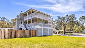A two-story building with a balcony on the upper floor, a covered outdoor area, and a fenced yard. - Gulf Shores Family Getaway! River View w/ Pool (Gulf Shores)