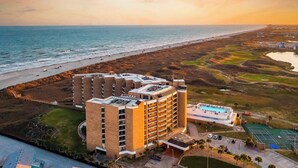 Um hotel com vários andares, piscina e vista para a praia e o oceano.