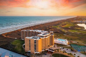 Un hôtel à plusieurs étages, doté d’une piscine et offrant une vue sur la plage et l’océan.
