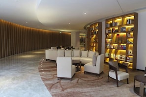 En moderne lobby med et buet siddeområde, en stor reol og et mønstret tæppe.