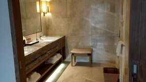 Ein Badezimmer mit Holzwaschtisch, einer Bank, einem großen Spiegel und einer Wandleuchte.