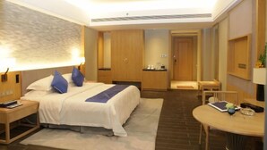 Ein Hotelzimmer mit Bett, Nachttisch, Lampe und Schreibtisch mit Stuhl.
