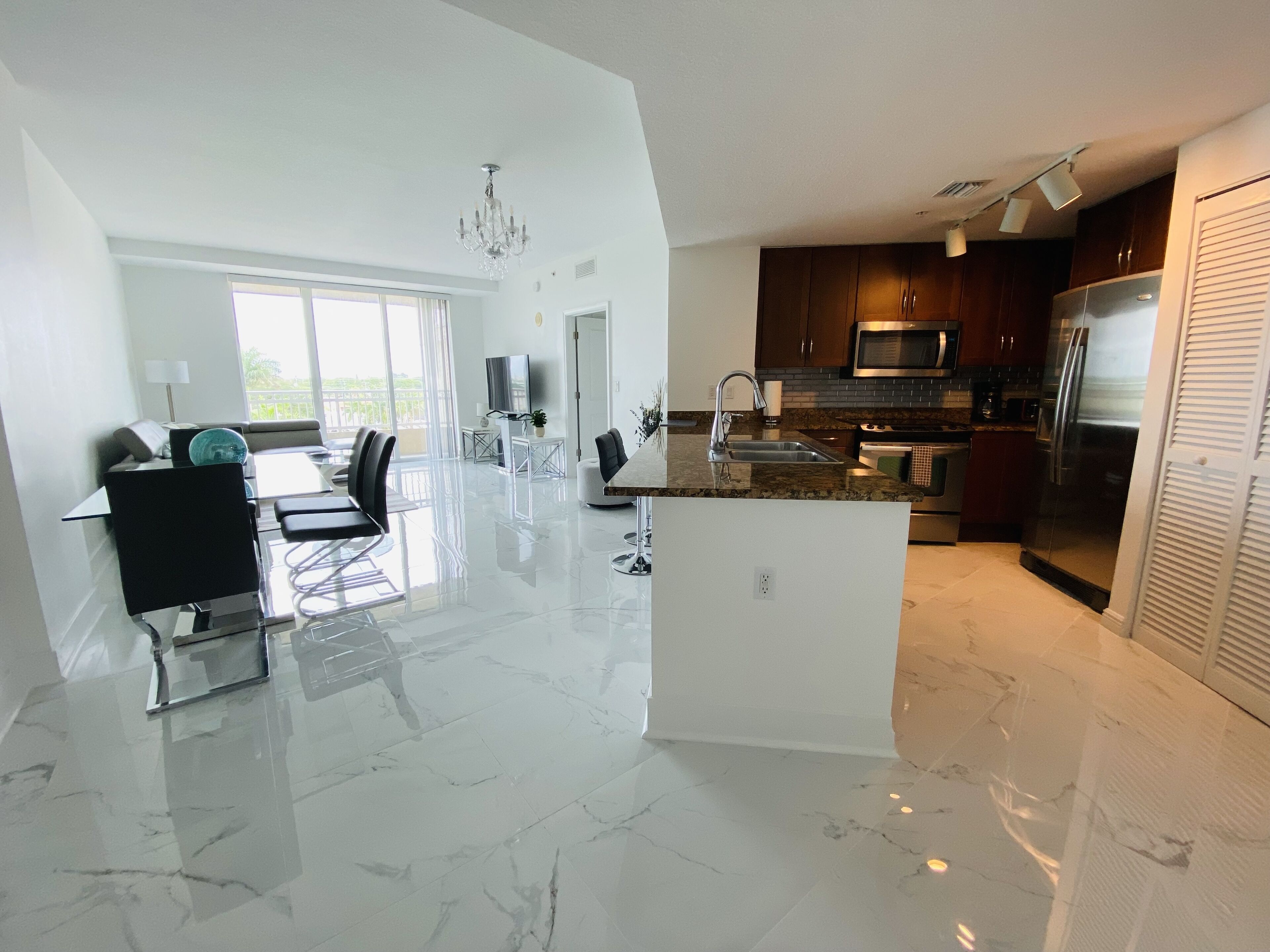A modern kitchen with a central island, a dining area with a view, and a large window.