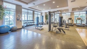 A gym with cardio machines, weightlifting equipment, and dumbbells. - Serenity Ocean Luxury Condo (Boynton Beach)