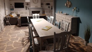 Un comedor con una mesa larga, sillas, chimenea y televisor montado en la pared.