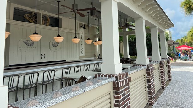 An outdoor bar area with a counter, chairs, and hanging pendant lights.