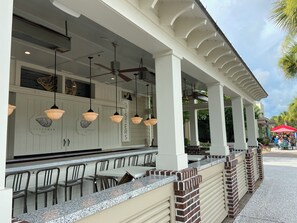 Un espace bar extérieur avec un comptoir, des chaises et des lampes suspendues.