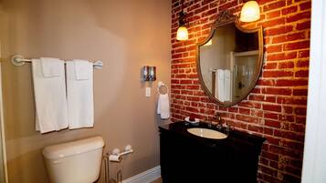 Een badkamer met toilet, wastafel en een spiegel aan een bakstenen muur.