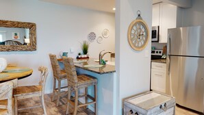 Een moderne keuken met een roestvrijstalen koelkast, een houten kookeiland met een spoelbak, rieten stoelen en decoratieve borden aan de muur.