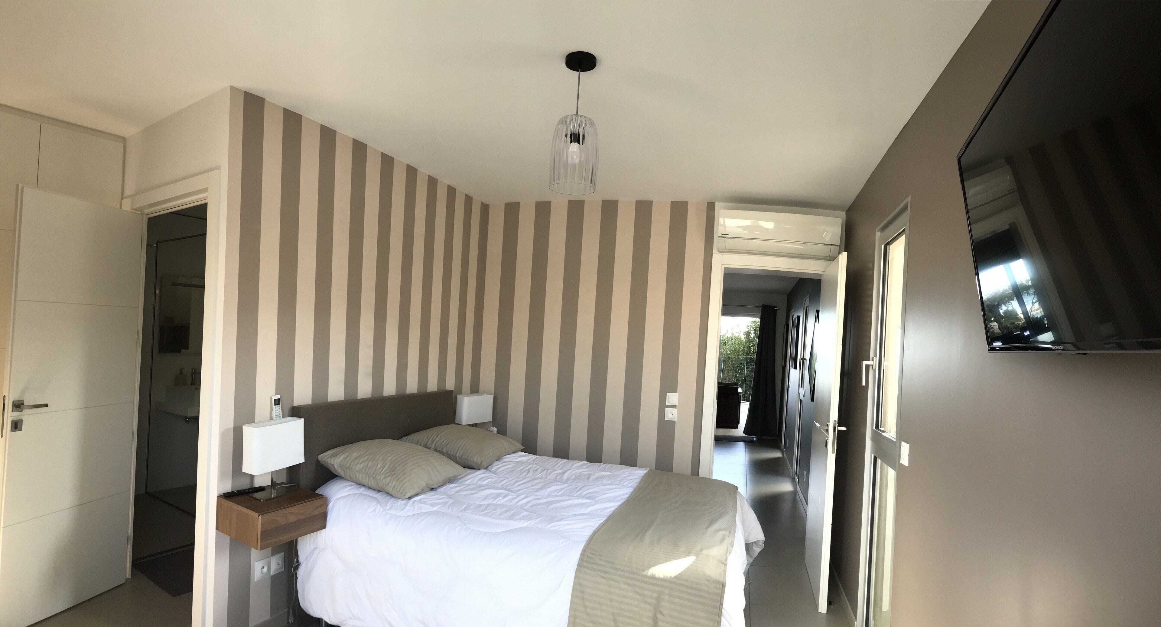Ein modernes Hotelzimmer mit einem großen Bett, einem Nachttisch und einem Spiegel.