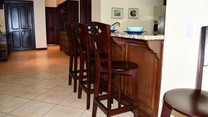 Une cuisine avec des chaises en bois, un plan de travail et un réfrigérateur.