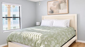 A bedroom with a bed, a ceiling fan, a window with blinds, and a painting on the wall.