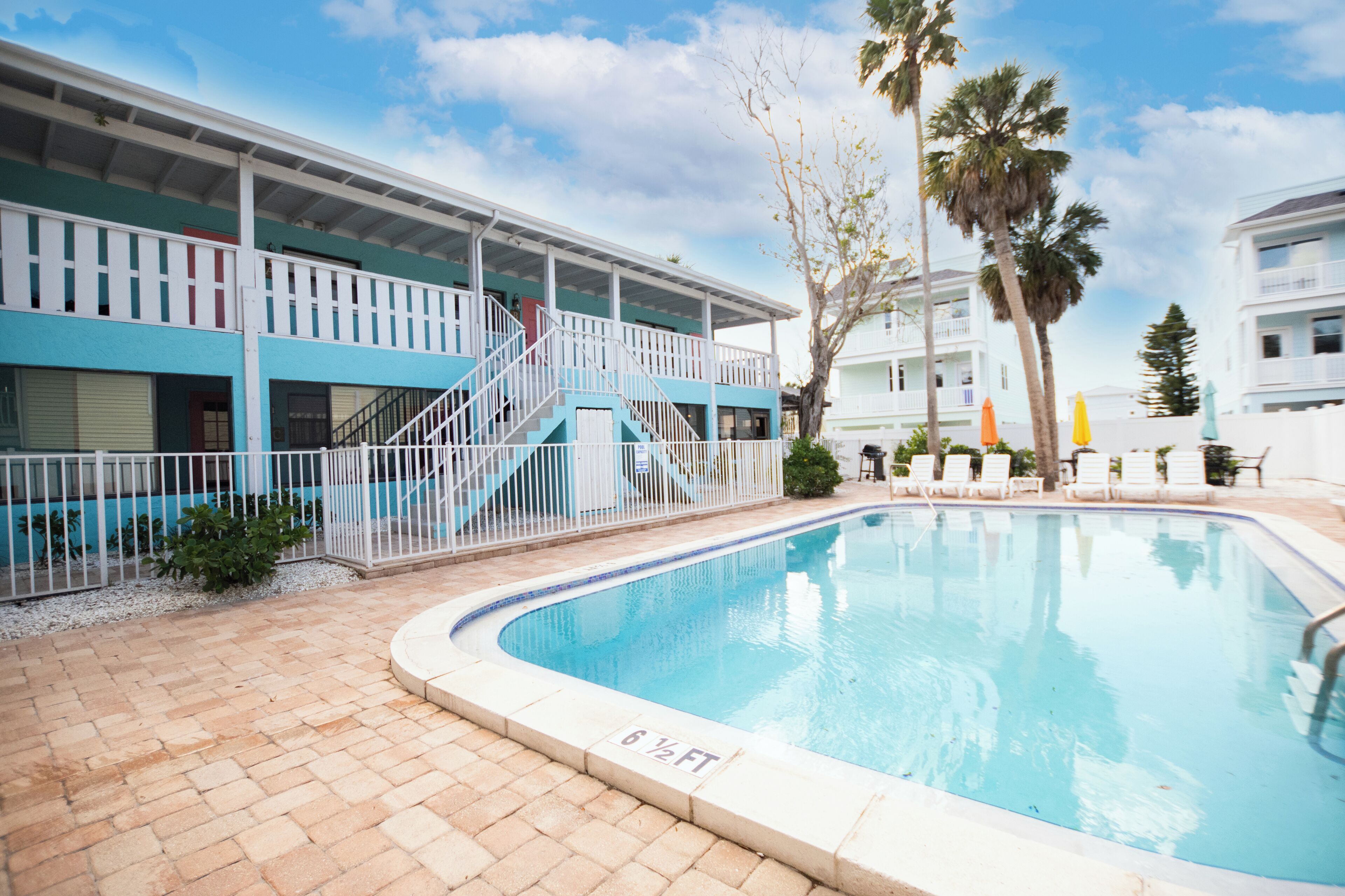A swimming pool with a 6 1/2 ft depth, a covered deck with stairs, and a white fence.