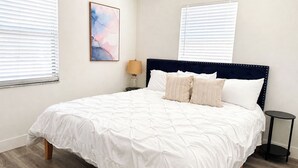 Une chambre à coucher avec un lit queen-size, une tête de lit, une table de chevet et une lampe.