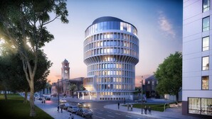 A modern building with a curved facade, large windows, and a clock tower in the background. - Crystalbrook Kingsley (Newcastle)