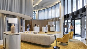 A modern hotel lobby with a reception desk, a large sofa, and a reception area. - Crystalbrook Kingsley (Newcastle)