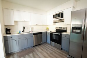 A modern kitchen with white cabinets, stainless steel appliances, and a dishwasher.