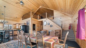 Eine geräumige Holzhütte mit Essbereich, Küche und einer Treppe zu einem Schlafboden.