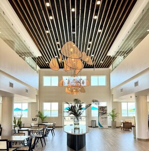 A spacious lobby with a high ceiling, modern lighting fixtures, and a central island with a plant.