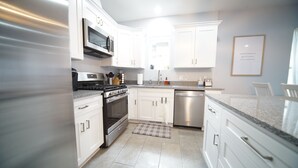 A modern kitchen with white cabinets, stainless steel appliances, and a granite countertop.