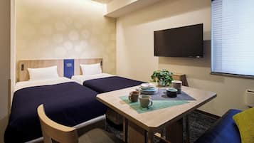 Quarto de hotel com duas camas, uma mesa com jogos de chá, uma planta e uma televisão na parede.