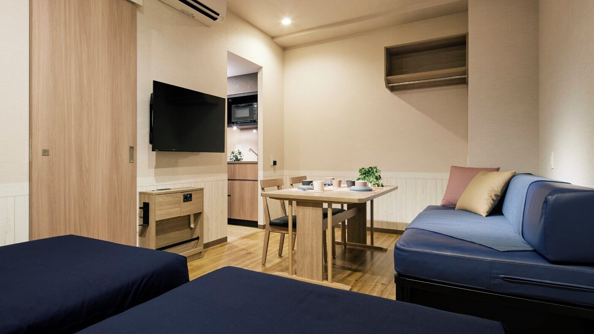 A compact room with a kitchenette, a dining area, and two beds.