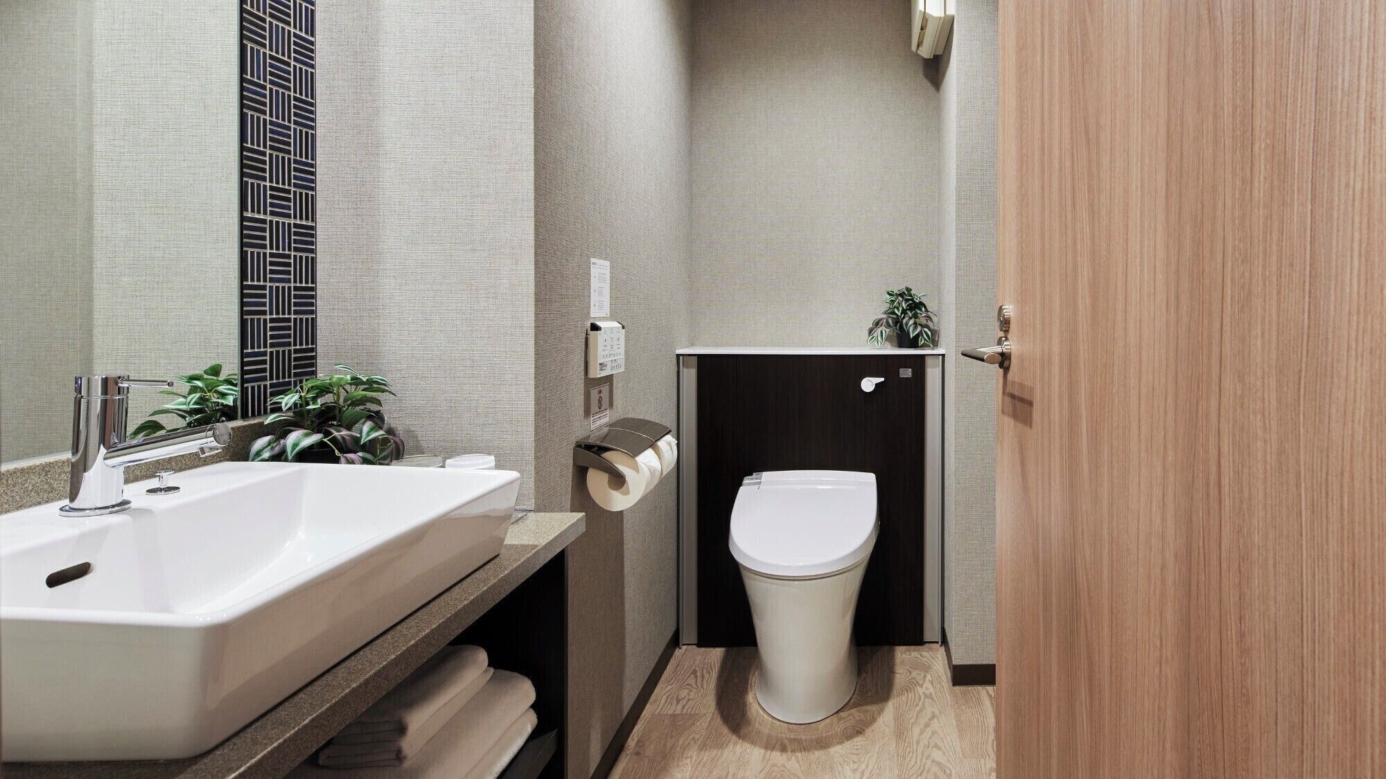 Ein modernes Badezimmer mit einem weißen Waschbecken, einer Toilette und einer Holztür.