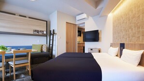 A hotel room with a bed, a desk, a chair, a TV, and an air conditioning unit. - Minn Kasai (Tokyo)