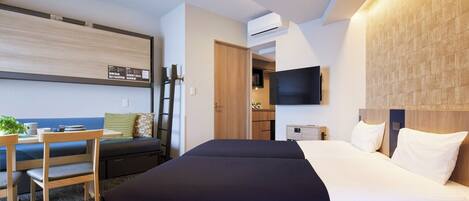 A hotel room with a bed, a desk, a chair, a TV, and an air conditioning unit.