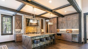 A spacious kitchen with a large island, stone accents, and wooden beams. - Bound to Impress. Private Hot Tub, Golf Access & Exclusive Club Amenities! (Truckee)