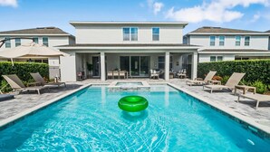 Une piscine avec des chaises longues et un grand flotteur gonflable vert.
