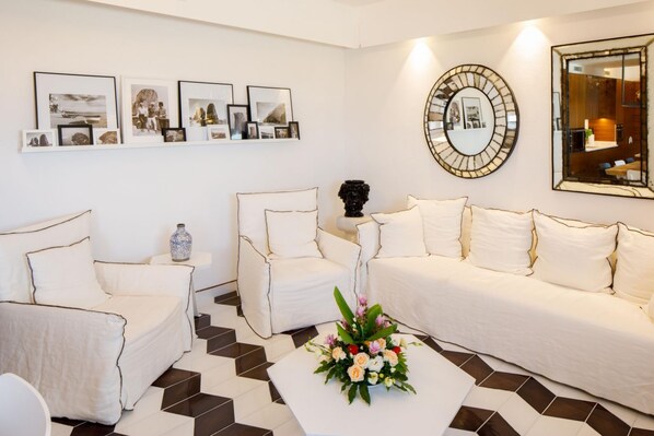 Una sala moderna con un sofá blanco, una mesa de centro con un centro de flores y cuadros en la pared.