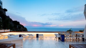 An outdoor terrace with lounge chairs and a dining area overlooking the sea. - Amalfi Coast Luxury Villa with Swimming Pool (Praiano)