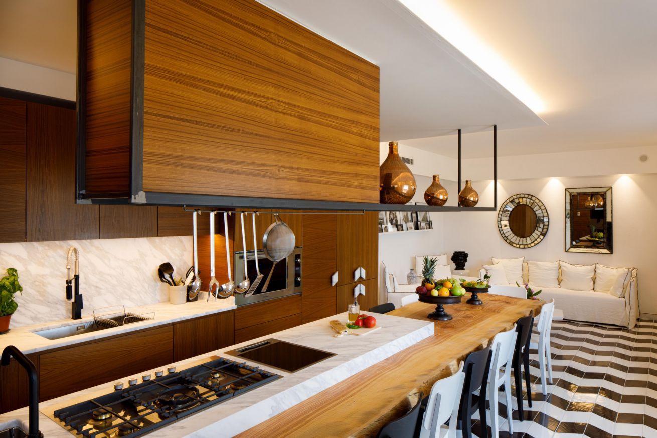 A modern kitchen with a wooden countertop, a built-in stove, and a dining area with a striped floor.