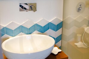 A bathroom with a large white basin, a mirror, and a wall with blue and white tiles.