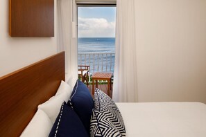 A bedroom with a wooden headboard, white bedding, and a view of the sea through a balcony. - Amalfi Coast Luxury Villa with Swimming Pool (Praiano)