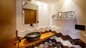 A modern bathroom with a wooden vanity, a black vessel sink, a mirror, and a wall-mounted shelf with framed pictures. - Amalfi Coast Luxury Villa with Swimming Pool (Praiano)