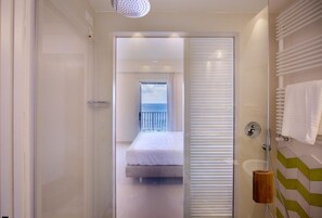 Ein Hotelzimmer mit Balkon, einem Bett und einer Duschkabine.