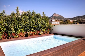 A rooftop swimming pool with a view of a mountain and surrounding buildings.