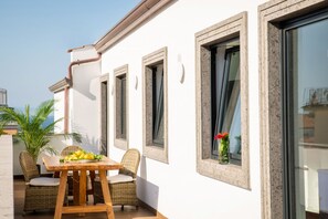 Un balcon agrémenté de meubles en osier, une table avec des fruits et une plante en pot.