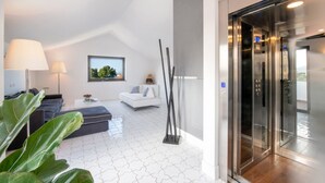 Habitació d'hotel moderna amb un paviment de disseny estel·lat, un sofà, una taula de cafè, una làmpada i vista a l'exterior a través d'una finestra.