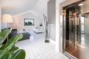 A modern hotel room with a white star-patterned floor, a sofa, a coffee table, a lamp, and a view of the outdoors through a window. - MyExclusiveItaly - Luxury Apartment with Penthouse and Pool (Sant'Agnello)