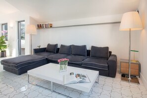 A modern living room with a sectional sofa, a coffee table, and two floor lamps. - MyExclusiveItaly - Luxury Apartment with Penthouse and Pool (Sant'Agnello)