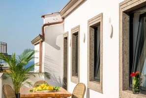 Ein Balkon mit Esstisch, einem Blumentopf und Blick aufs Meer.