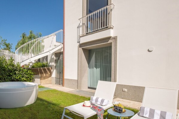 A modern outdoor area with a pool, lounge chairs, and a small table with a fruit bowl.