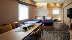 A hotel room with two beds, a dining table, and a TV.