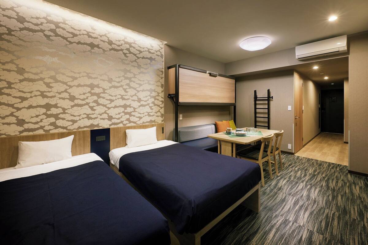 Ein Hotelzimmer mit zwei Betten, einem Schreibtisch und einem kleinen Tisch.